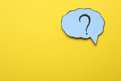 Photo of Paper speech bubble with question mark on yellow background, top view. Space for text