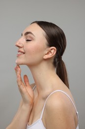 Smiling woman touching her chin on grey background