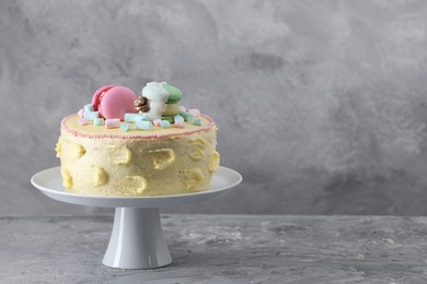 Photo of Delicious cake decorated with macarons and marshmallows on grey table, space for text