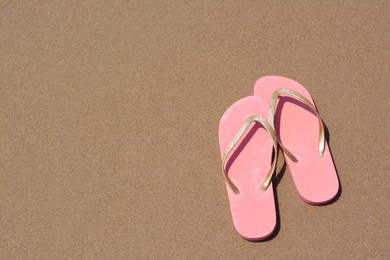 Stylish pink flip flops on wet sand, above view. Space for text