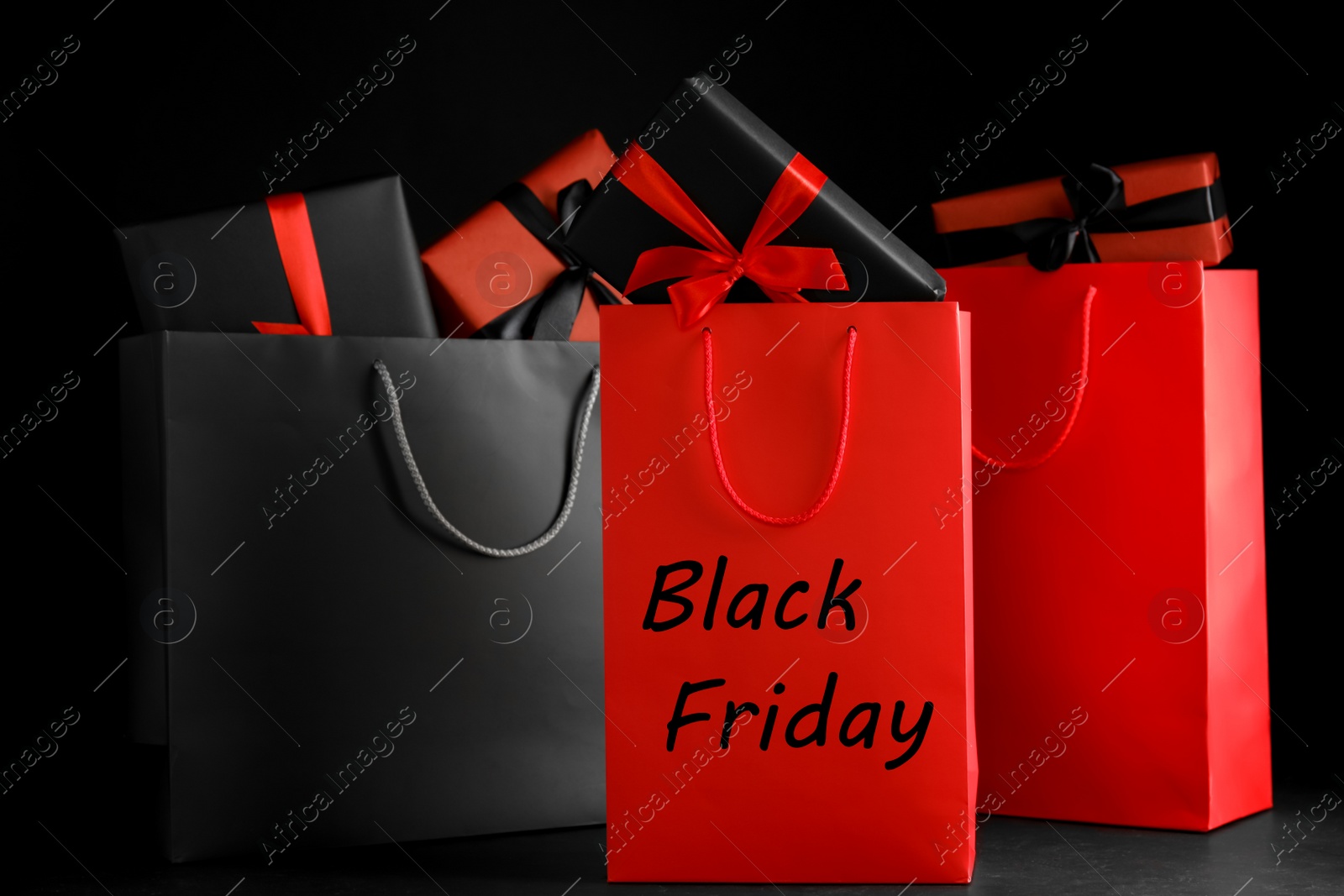 Photo of Paper shopping bags and gift boxes on dark background. Black Friday sale