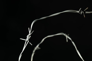 Photo of Metal barbed wire on black background, closeup