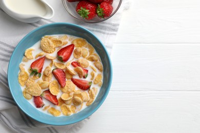 Bowl of tasty crispy corn flakes with milk and strawberries on white wooden table, flat lay. Space for text