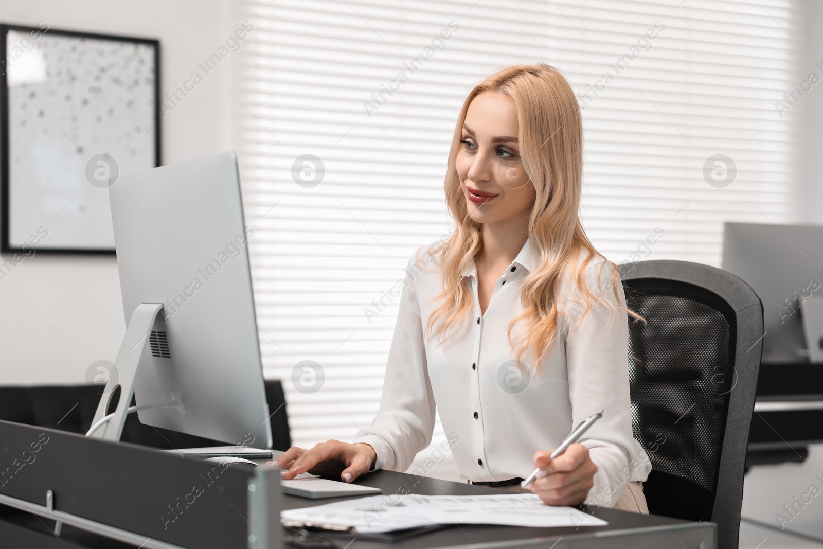 Photo of Secretary working on computer at table in office