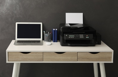 Photo of New modern printer, laptop and office supplies on white table