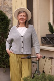 Photo of Beautiful senior woman standing near bicycle outdoors
