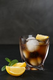 Photo of Delicious cocktail with lemon, ice balls and mint on black table, space for text