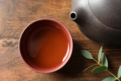 Photo of Cup of freshly brewed oolong tea on wooden table, top view
