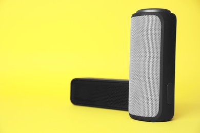 Photo of Portable bluetooth speakers on yellow background, space for text. Audio equipment