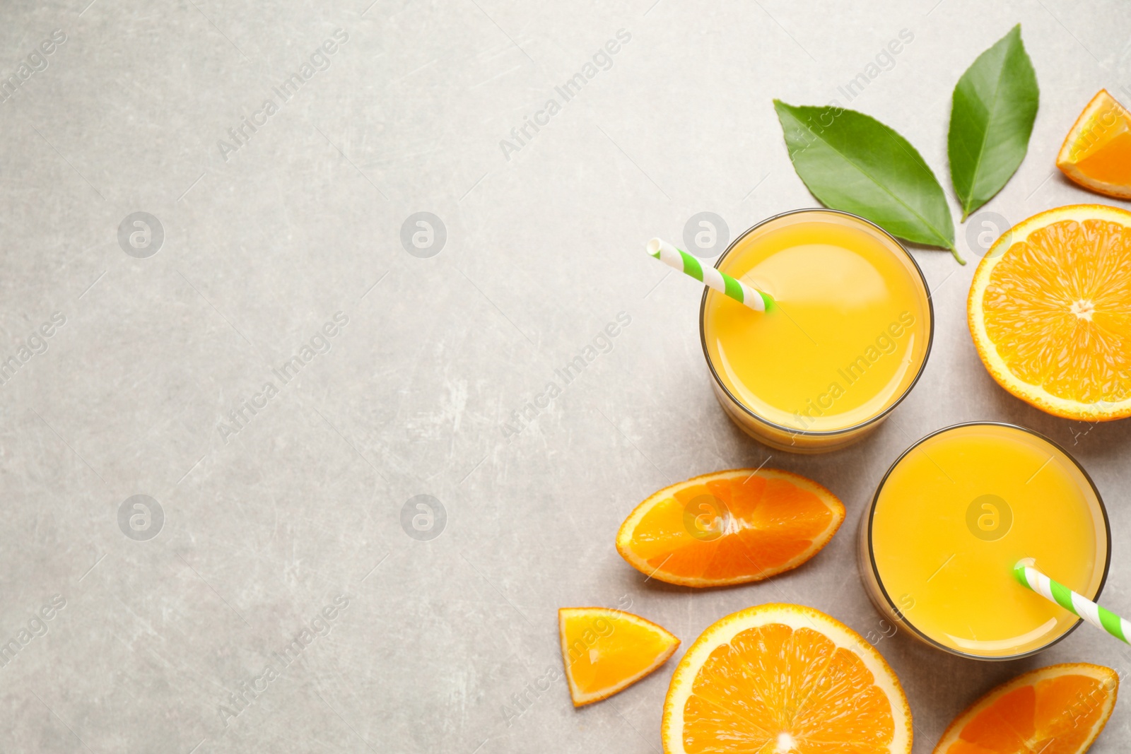 Photo of Glasses of orange juice and fresh fruits on light grey table, flat lay. Space for text