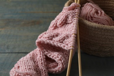 Photo of Soft pink woolen yarn, knitting and needles on wooden table, closeup. Space for text