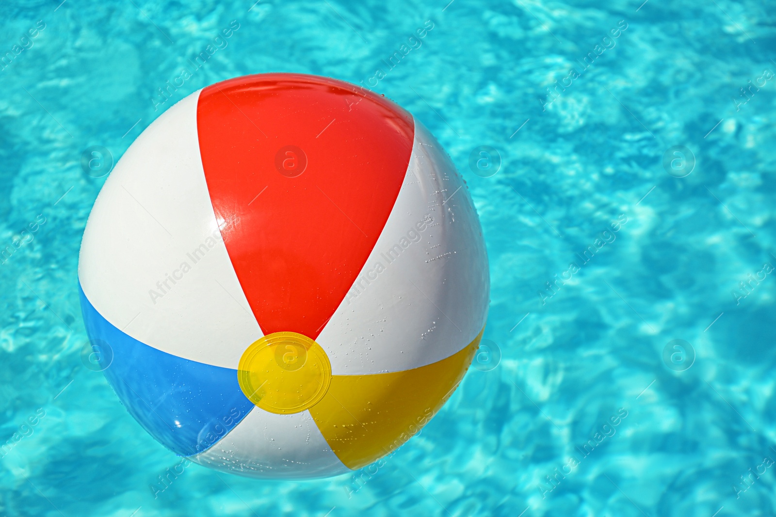 Photo of Colorful beach ball floating in swimming pool on sunny day. Space for text
