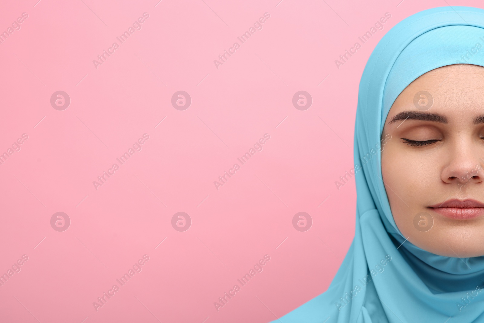 Photo of Muslim woman in hijab on pink background, closeup. Space for text