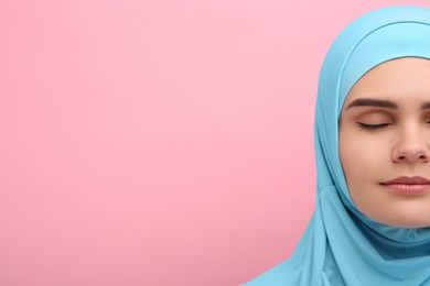 Photo of Muslim woman in hijab on pink background, closeup. Space for text