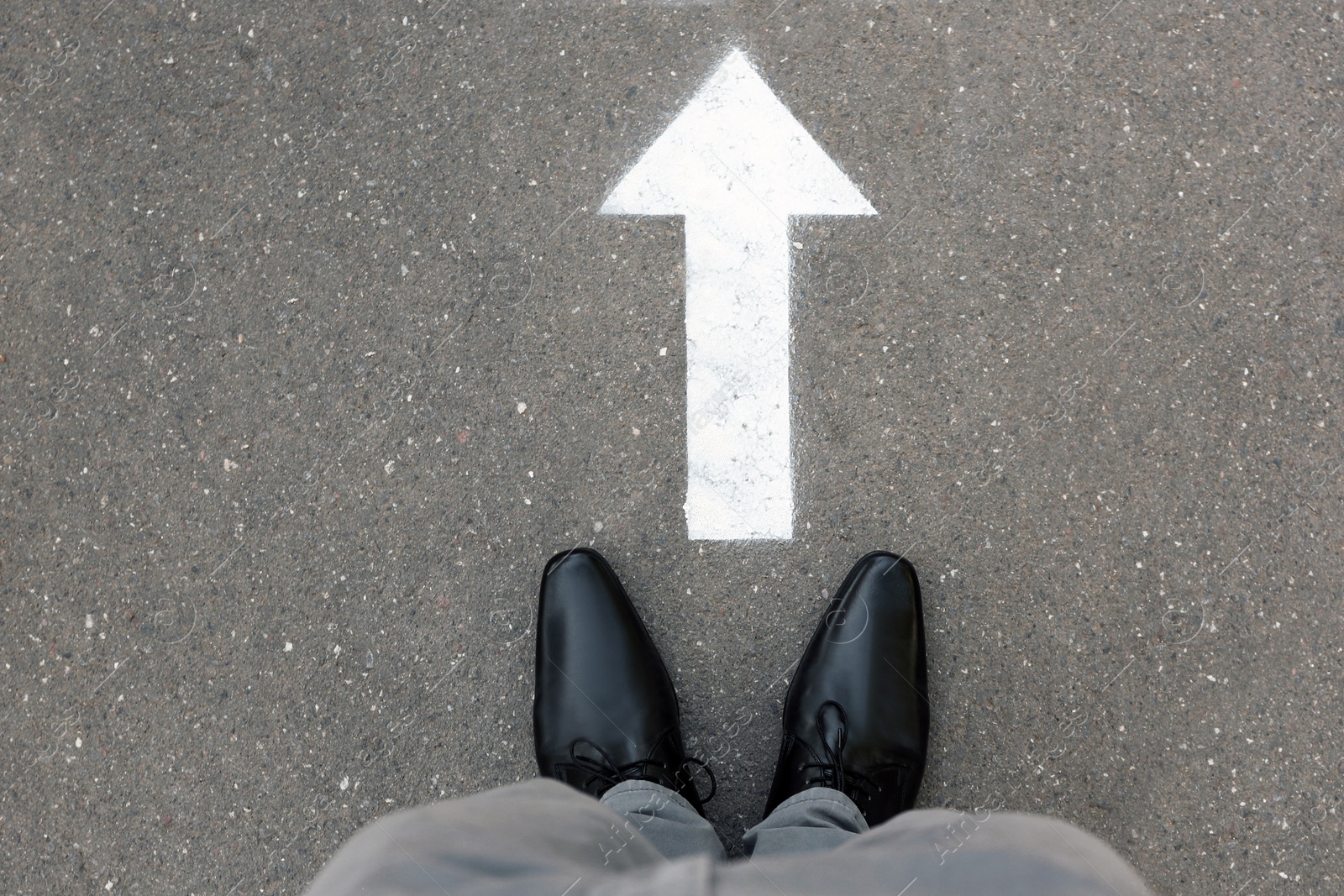 Photo of Man standing near arrow on asphalt, top view. Choice concept