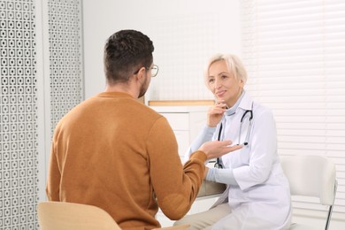 Photo of Doctor consulting patient at table in clinic