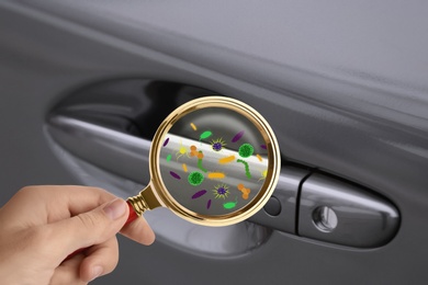 Woman with magnifying glass detecting microbes on car door handle, closeup