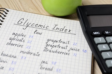Photo of Notebook with products of low, moderate and high glycemic index, calculator and apple on table, closeup