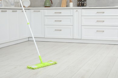 Photo of Cleaning of parquet floor with mop in kitchen, space for text