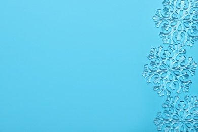 Photo of Beautiful decorative snowflakes on light blue background, flat lay. Space for text