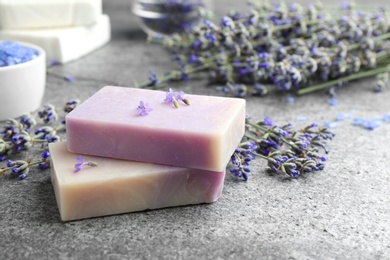Hand made soap bars with lavender flowers on grey stone table. Space for text