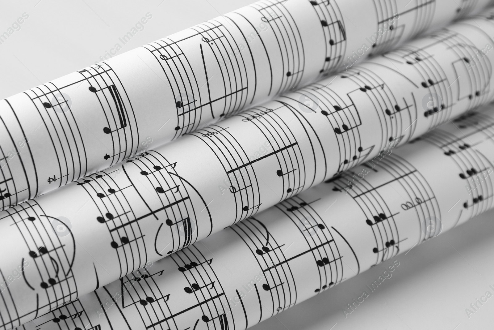 Photo of Rolled sheets with music notes on white background, closeup