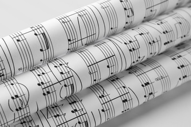 Photo of Rolled sheets with music notes on white background, closeup