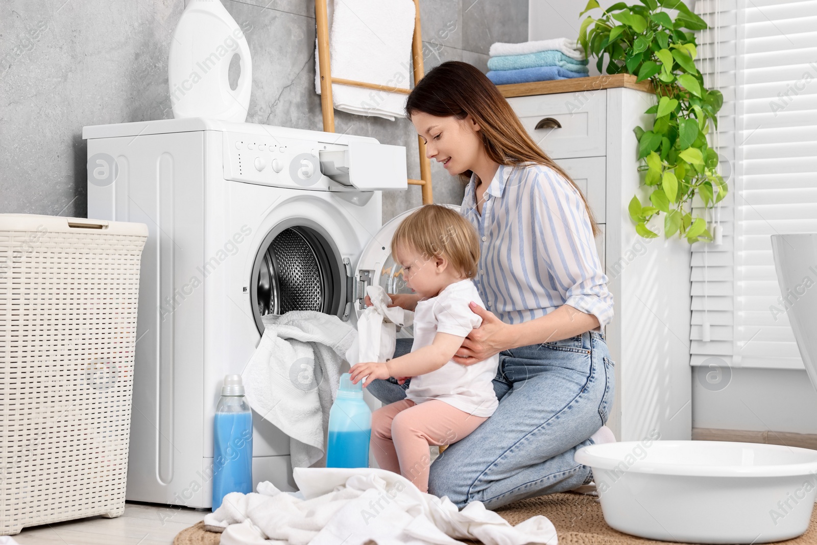 Photo of Mother with her daughter washing baby clothes in bathroom