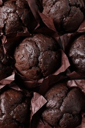 Tasty chocolate muffins as background, top view