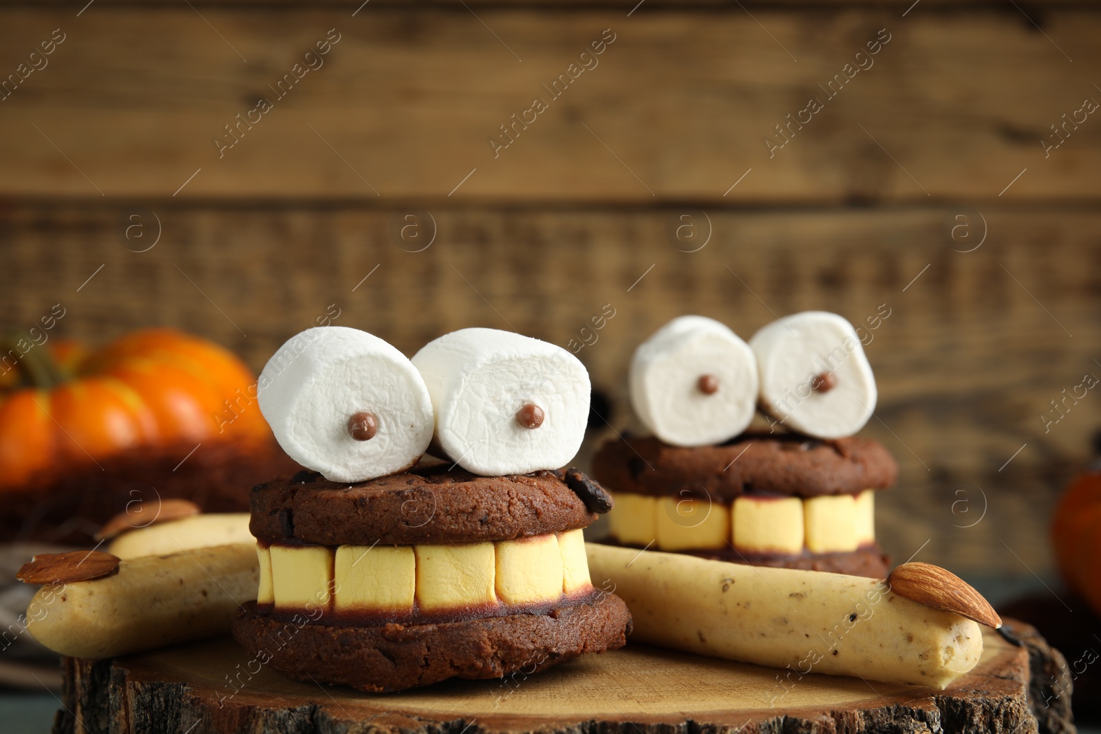 Photo of Delicious desserts decorated as monsters on stump, closeup. Halloween treat