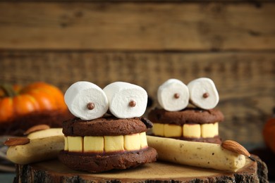 Photo of Delicious desserts decorated as monsters on stump, closeup. Halloween treat