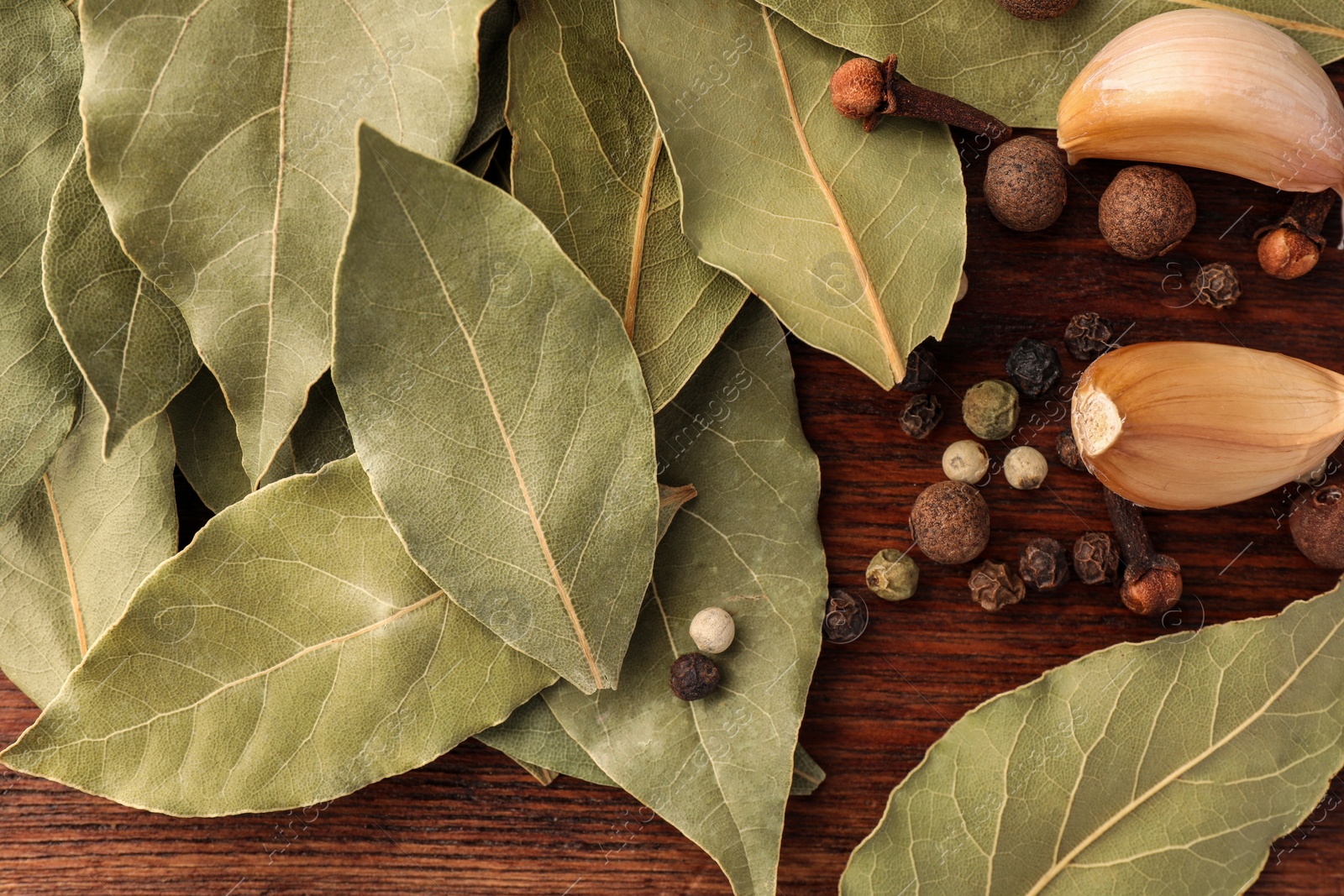 Photo of Aromatic bay leaves and spices on wooden table, flat lay