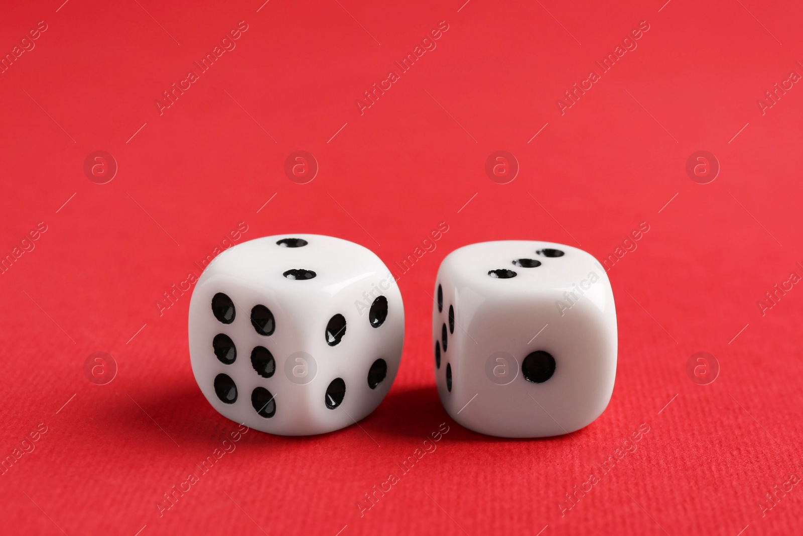 Photo of Two white game dices on red background, closeup