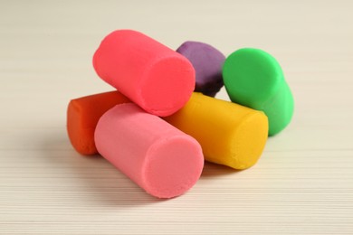 Different color play dough on wooden table, closeup