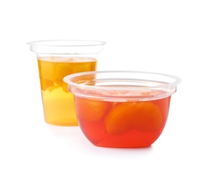 Photo of Tasty jelly desserts with pieces of fruits in plastic cups on white background