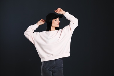 Photo of Portrait of young woman in sweater on black background. Mock up for design