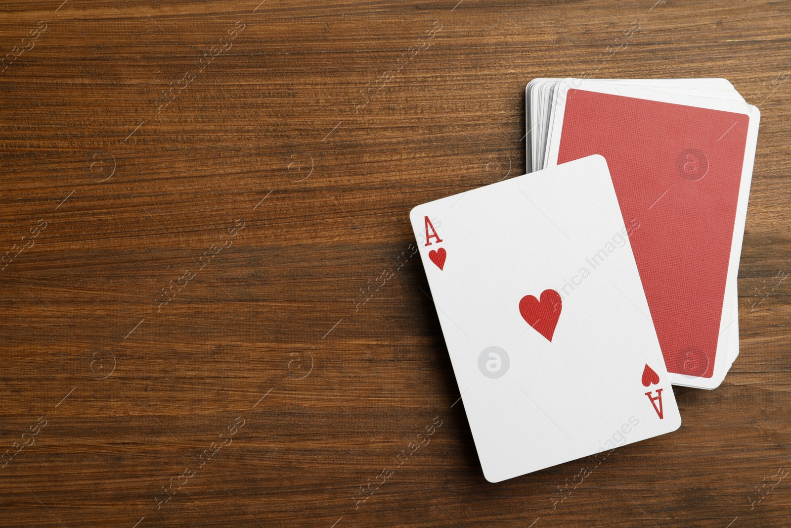 Photo of Deck of playing cards on wooden table, flat lay. Space for text