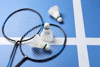 Photo of Feather badminton shuttlecocks and rackets on blue background. Space for text