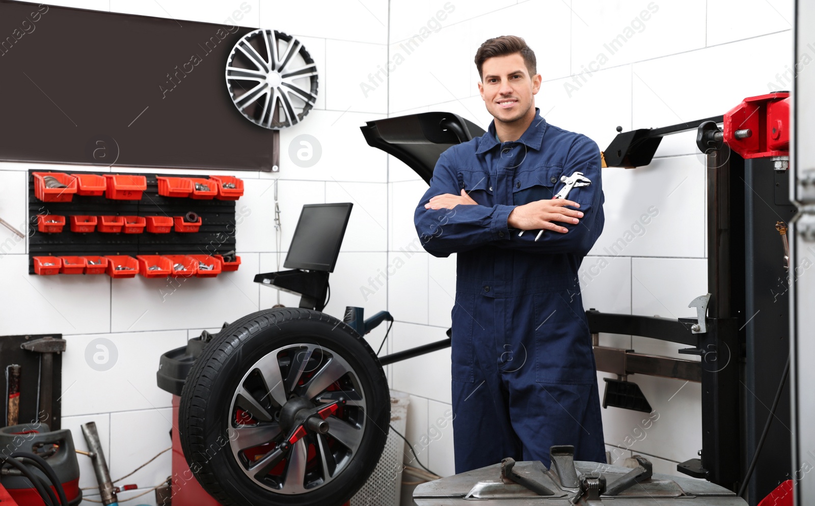 Photo of Professional worker with adjustable wrench in shop of modern tire service