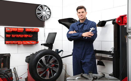 Photo of Professional worker with adjustable wrench in shop of modern tire service