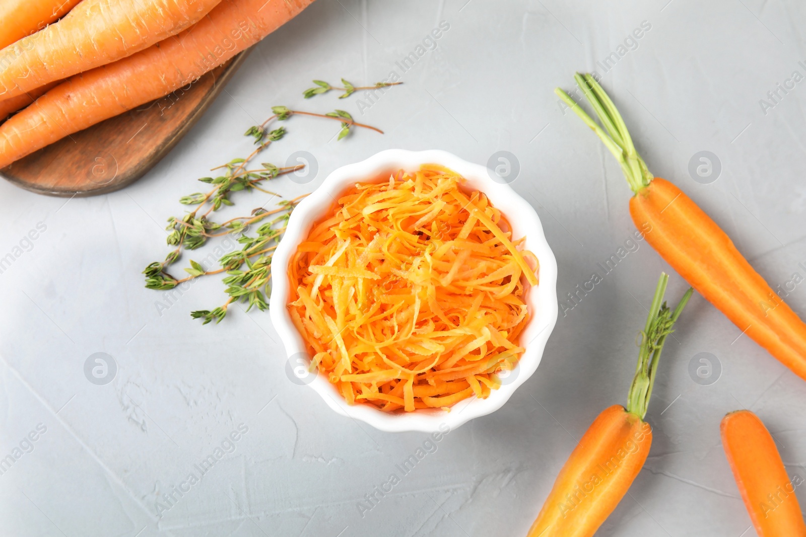 Photo of Bowl with grated ripe carrot and fresh vegetable on table, top view