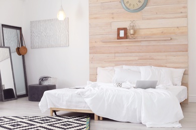 Room interior with comfortable bed near wooden wall