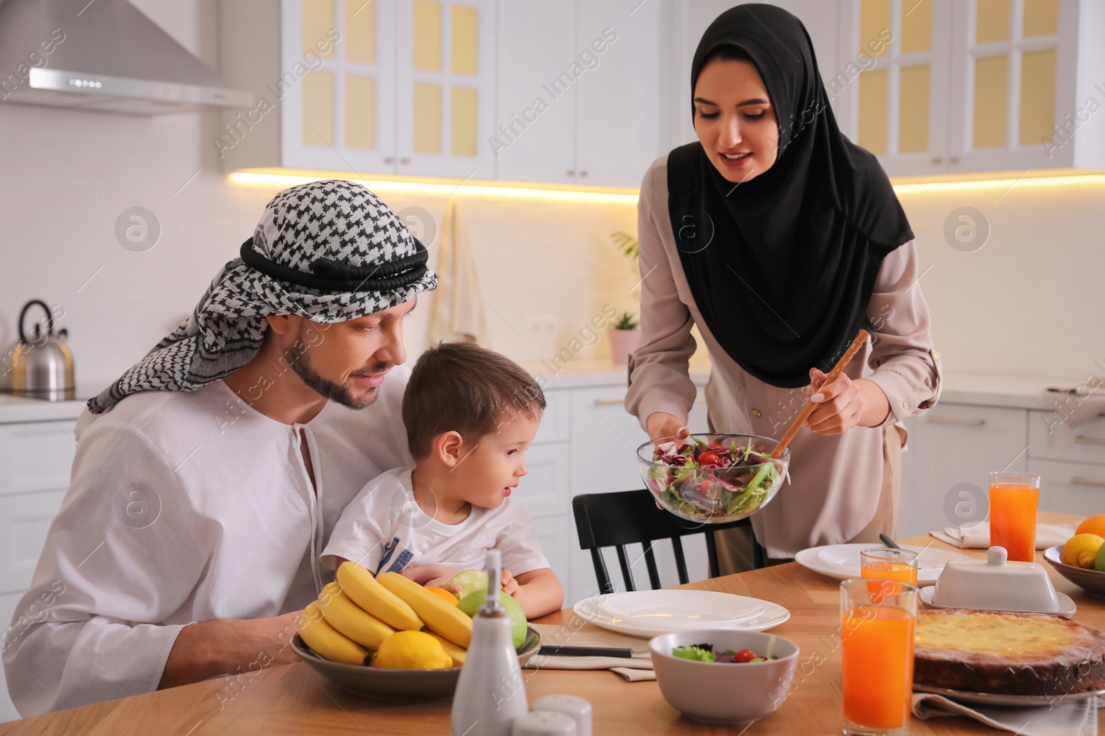 Photo of Happy Muslim family eating together in kitchen