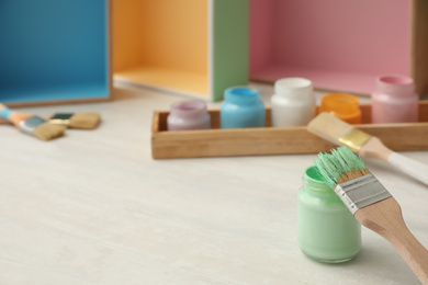 Photo of Jar of green paint and brush on white table. Space for text