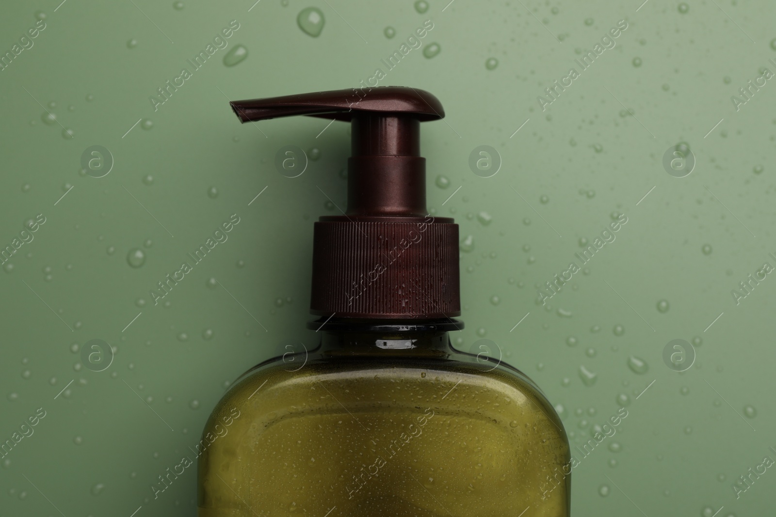 Photo of Bottle of face cleansing product on green background, top view