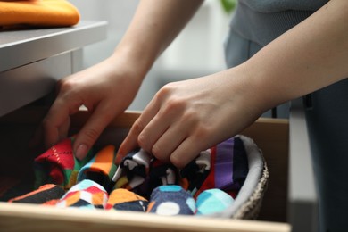 Photo of Woman putting socks into drawer indoors, closeup