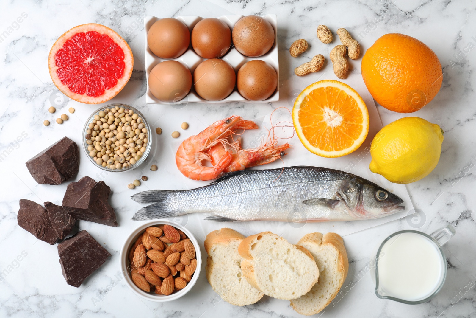 Photo of Flat lay composition of different products on white marble table. Food allergy concept