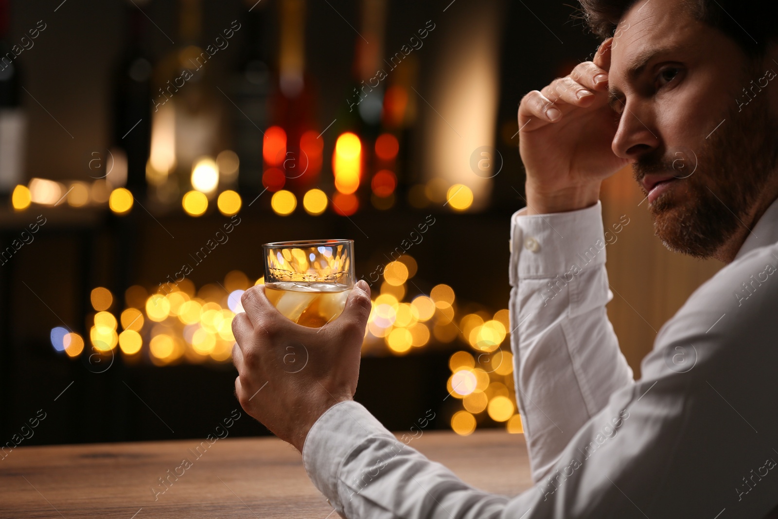 Photo of Man with glass of whiskey at bar counter against blurred lights. Space for text