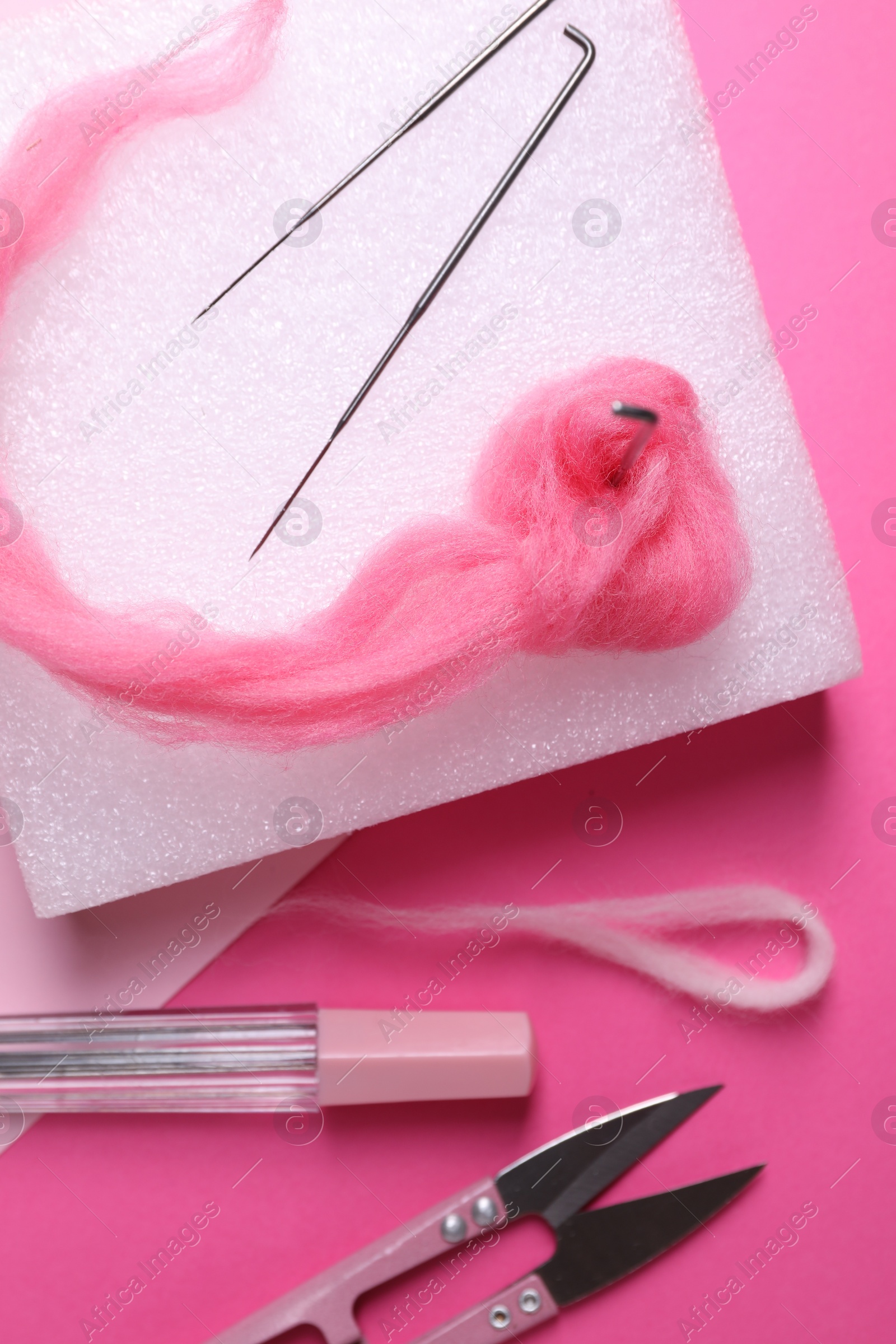 Photo of Flat lay composition with wool and needle felting tools on pink background