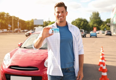 Photo of Man with license near car outdoors. Driving school